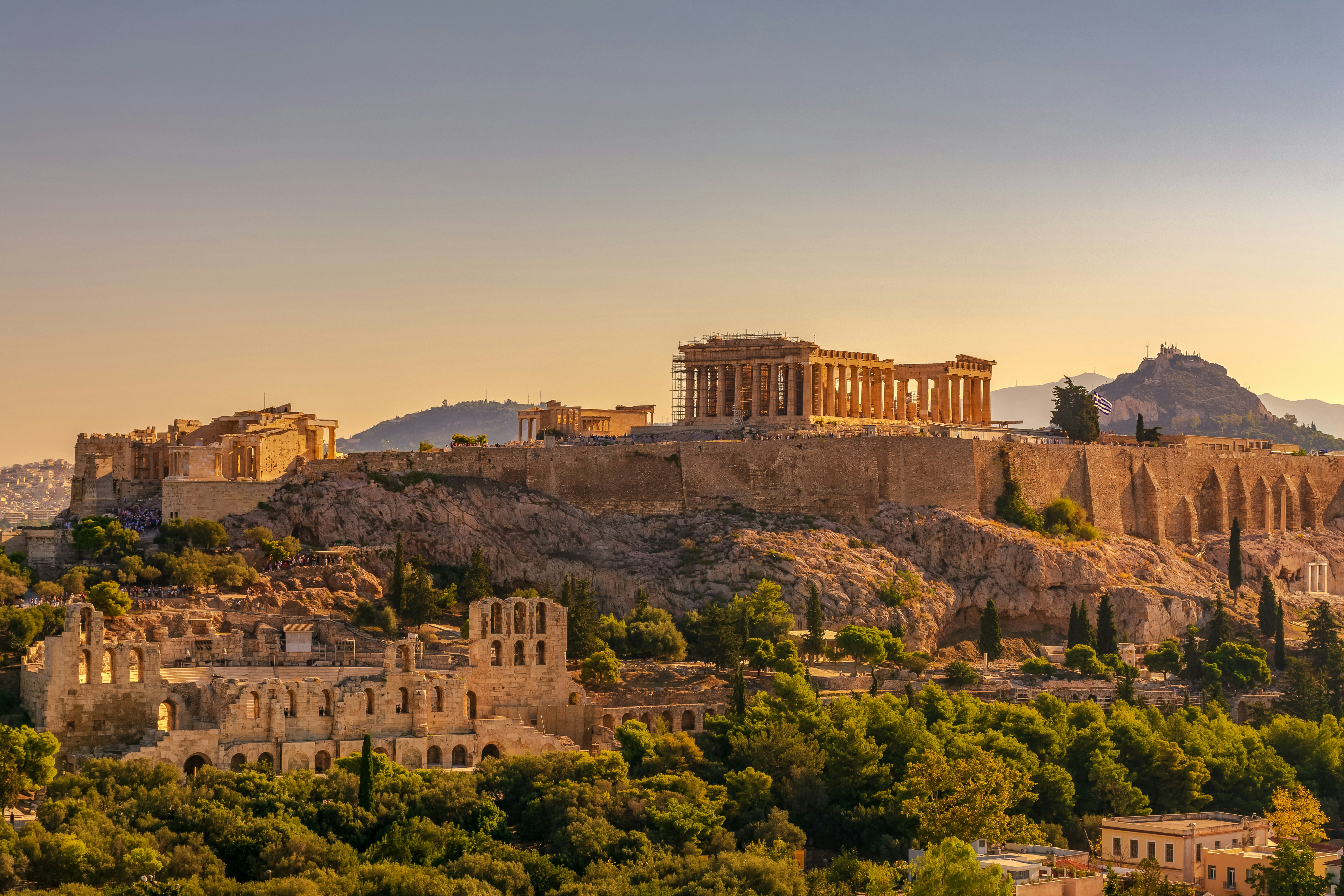 The Acropolis above Athens at golden hour, with Lycabettus Hill beyond.